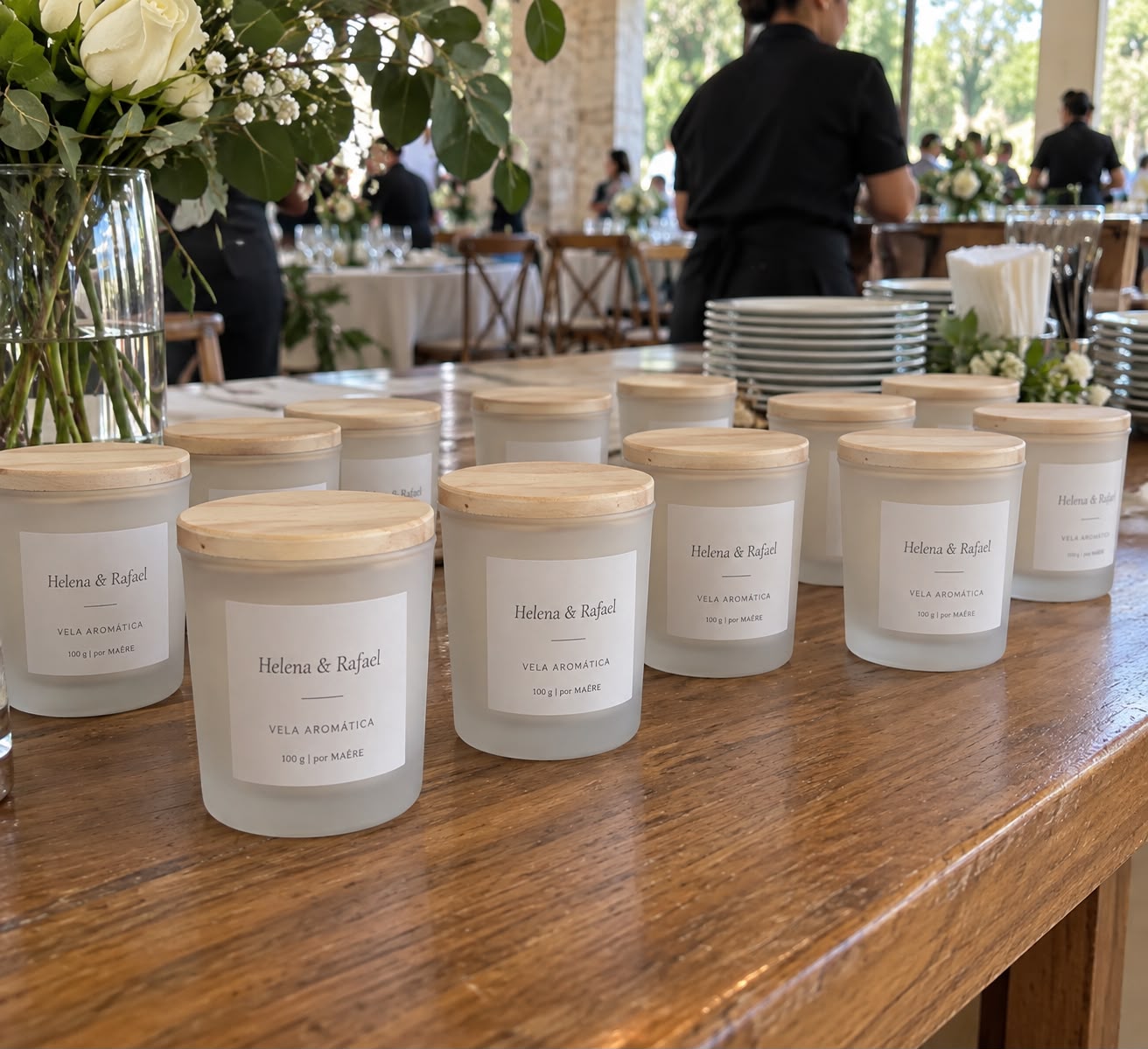 Velas aromáticas personalizadas Helena & Rafael dispostas em mesa de evento.